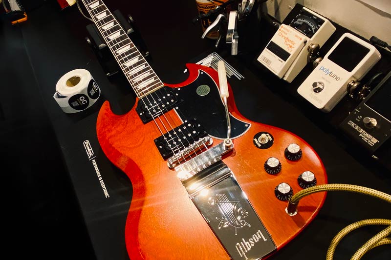Red Gibson electric guitar lying face up on workbench with tools