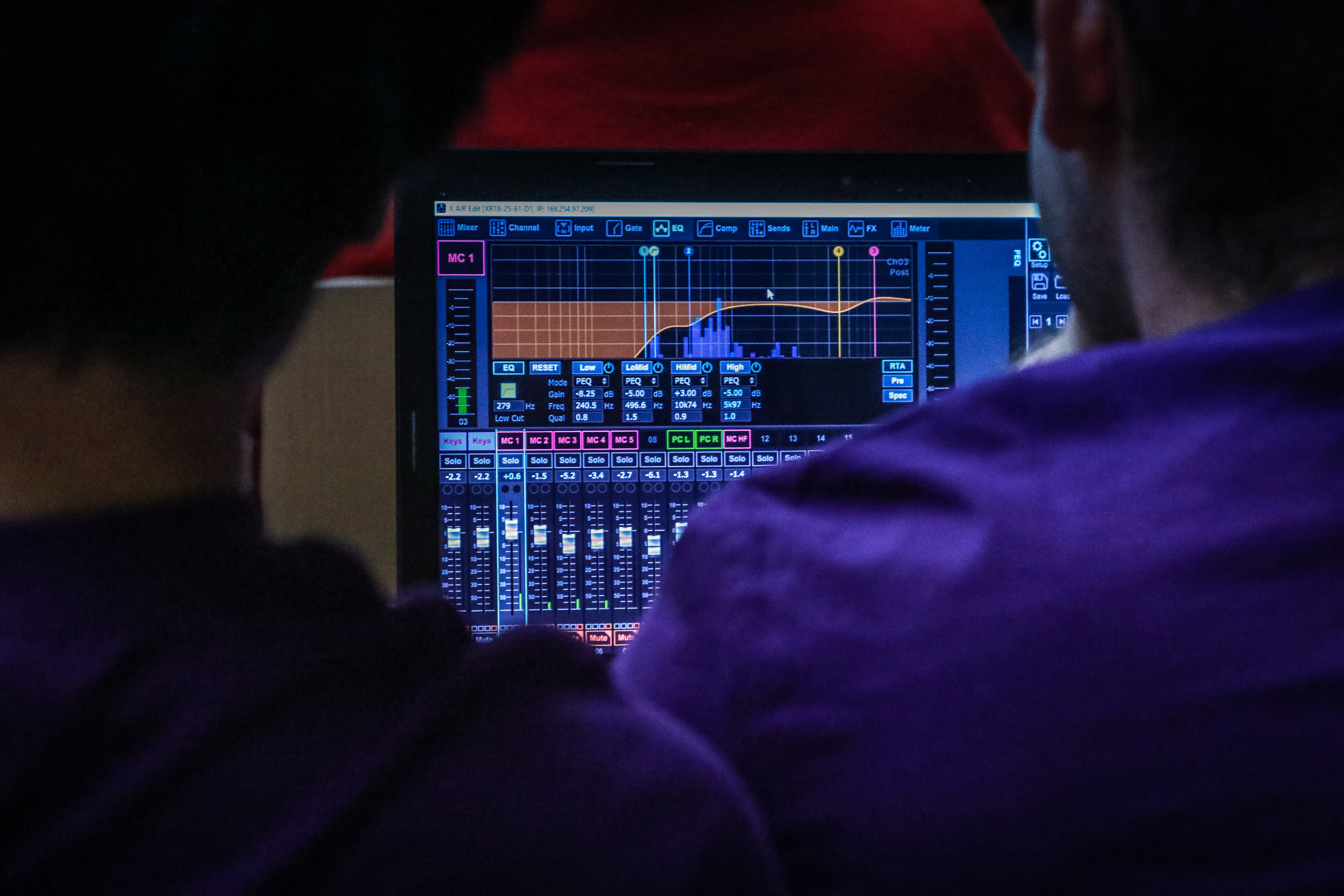 Two people adjusting EQ parameters on a DAW.