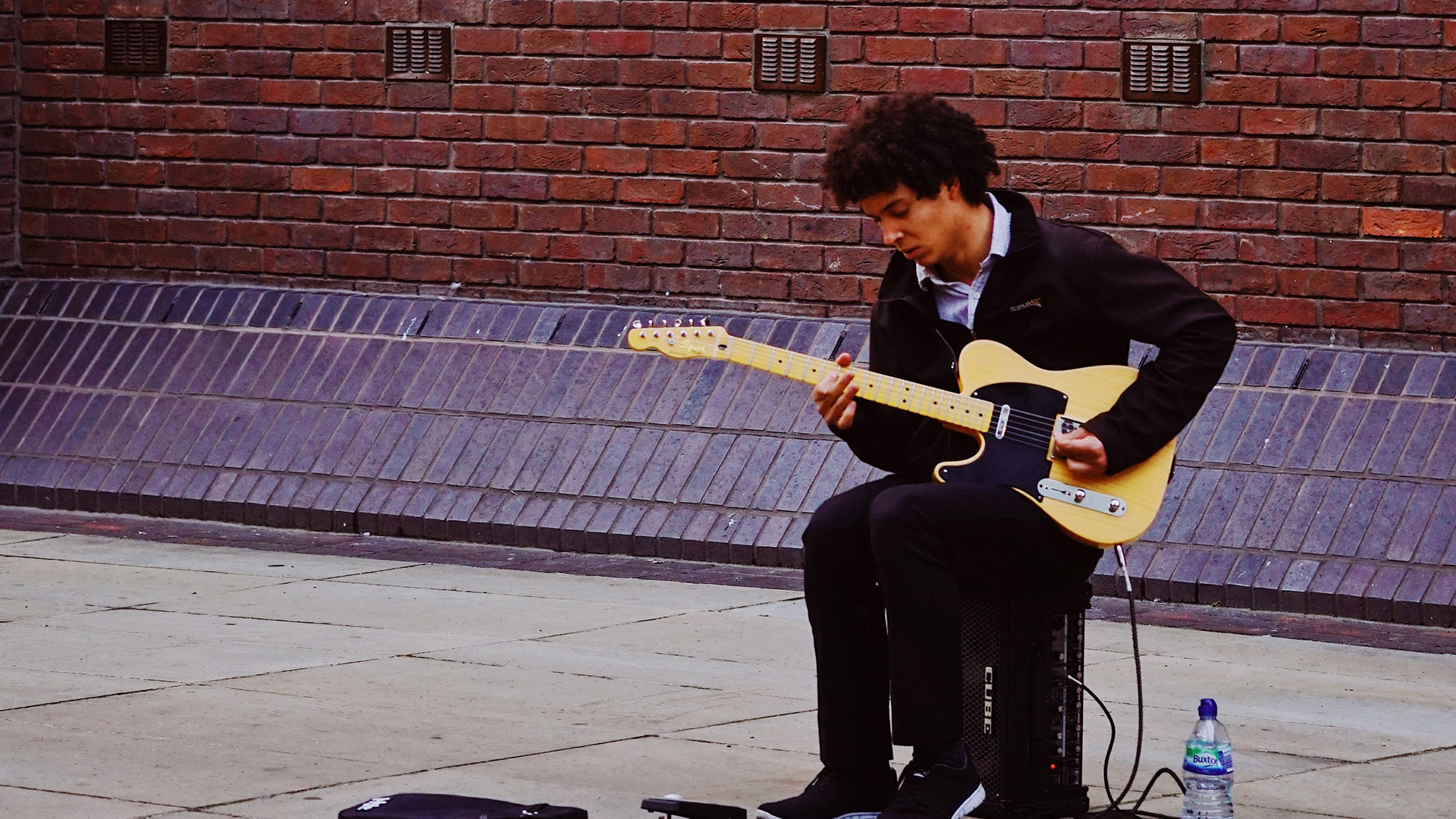 Busker sitting on a Roland Cube and playing Fender Telecaster