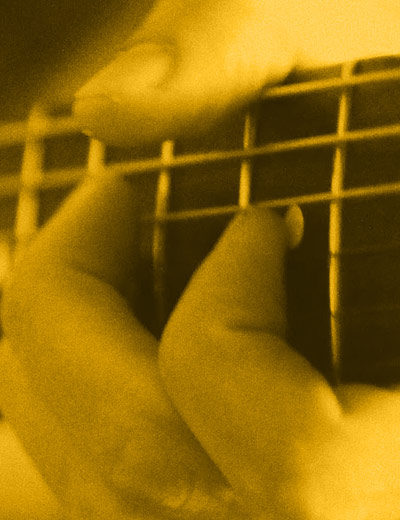 close up of hands playing guitar chord